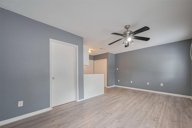 spare room featuring ceiling fan, baseboards, and light wood-type flooring