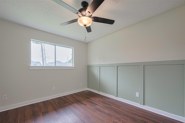 spare room featuring ceiling fan, a textured ceiling, wood finished floors, a wainscoted wall, and a decorative wall