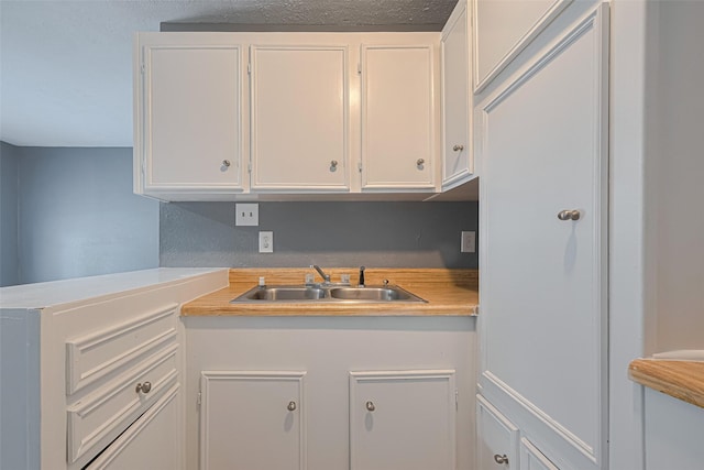 kitchen with a sink, white cabinets, and light countertops