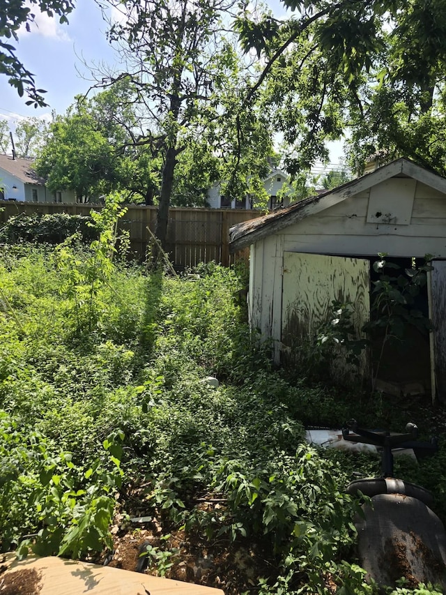 view of yard with an outdoor structure, fence, and a storage shed