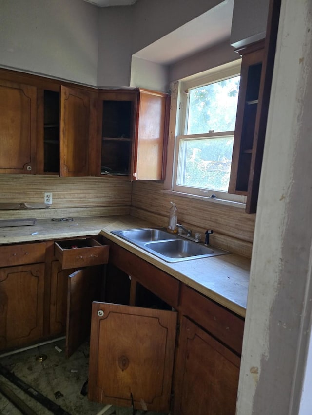 kitchen with a sink, light countertops, open shelves, and brown cabinets