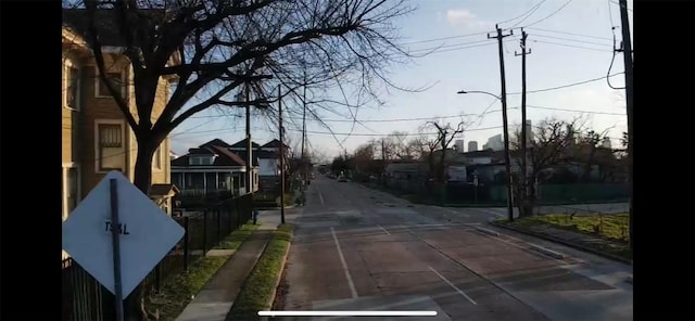 view of road featuring street lighting, a residential view, sidewalks, and curbs