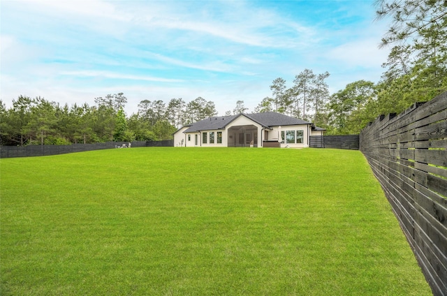 exterior space featuring a fenced backyard, a sunroom, and a yard