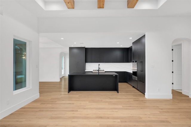 kitchen featuring stainless steel double oven, arched walkways, modern cabinets, a sink, and dark cabinets