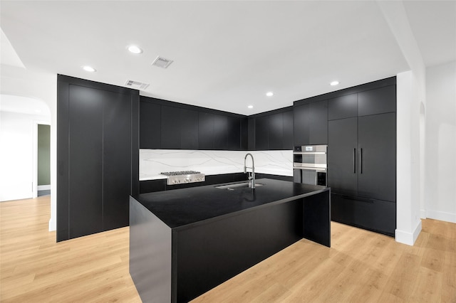 kitchen with dark cabinets, modern cabinets, light wood-style flooring, and visible vents
