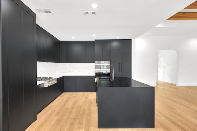 kitchen featuring dark cabinetry, a sink, modern cabinets, and visible vents
