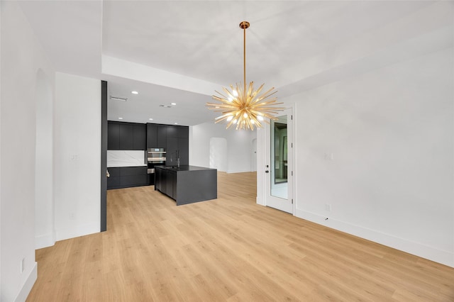 unfurnished living room with an inviting chandelier, a sink, light wood finished floors, recessed lighting, and baseboards