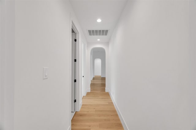 hall featuring light wood-style floors, arched walkways, recessed lighting, baseboards, and visible vents