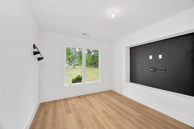 spare room featuring baseboards, light wood-style flooring, and visible vents