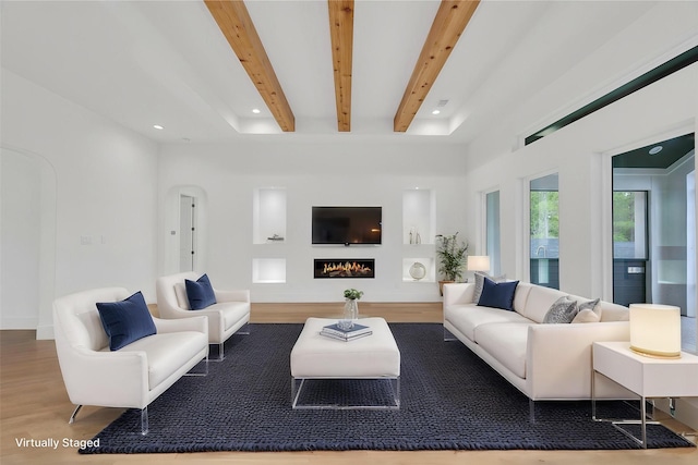 living room featuring recessed lighting, beamed ceiling, a lit fireplace, and wood finished floors