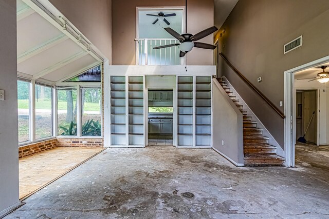 interior space featuring ceiling fan, visible vents, stairway, and high vaulted ceiling