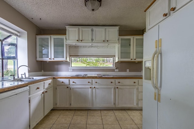 kitchen featuring a sink, light tile patterned floors, white appliances, and a textured ceiling