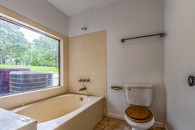 bathroom with baseboards, tile patterned flooring, a bath, and toilet