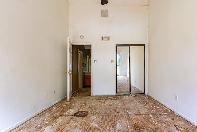 unfurnished bedroom featuring visible vents, a towering ceiling, and a closet