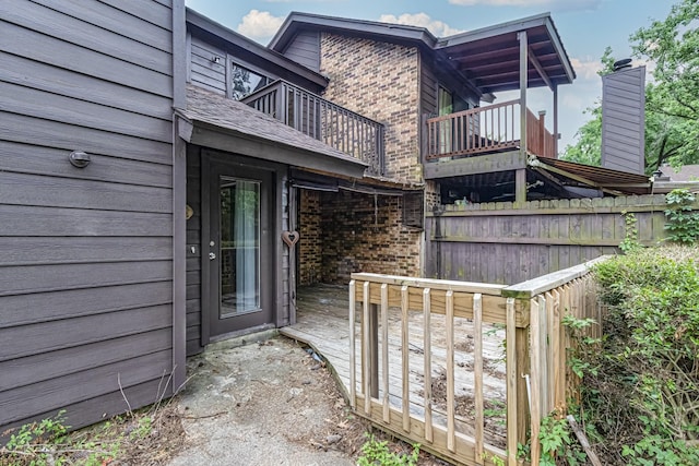 exterior space featuring brick siding, fence, and a balcony