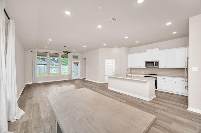 kitchen with visible vents, a ceiling fan, stainless steel microwave, tasteful backsplash, and a sink