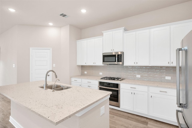 kitchen featuring visible vents, a sink, white cabinets, light wood finished floors, and stainless steel appliances