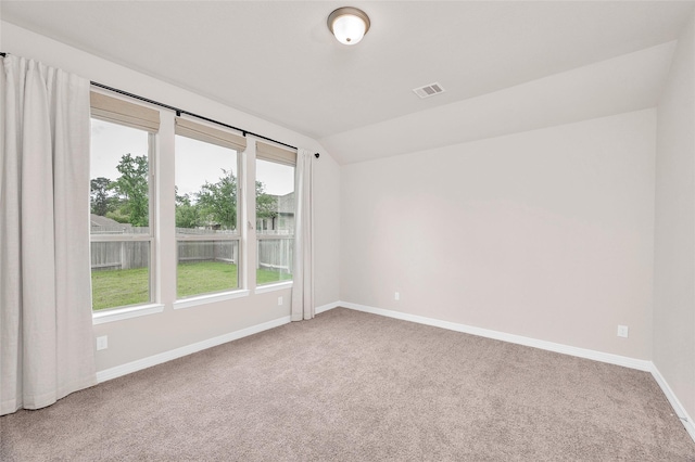 empty room featuring carpet flooring, baseboards, visible vents, and vaulted ceiling