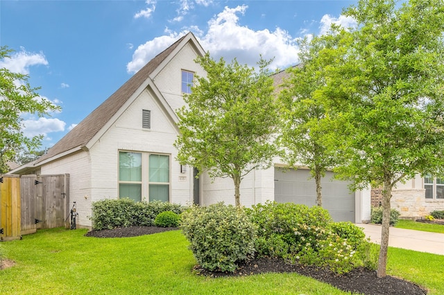 view of front facade featuring fence, a front yard, brick siding, a shingled roof, and concrete driveway