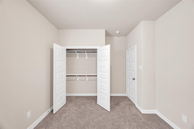 unfurnished bedroom featuring a closet, baseboards, and carpet flooring