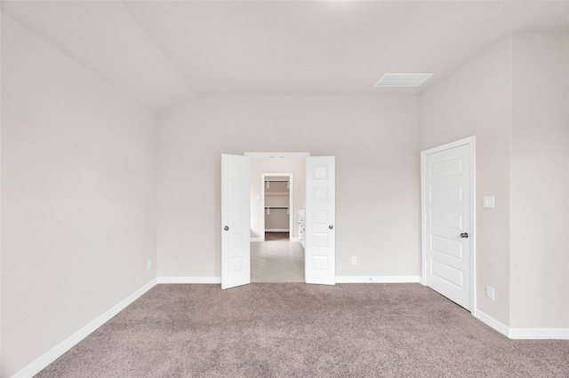 carpeted spare room featuring baseboards and vaulted ceiling