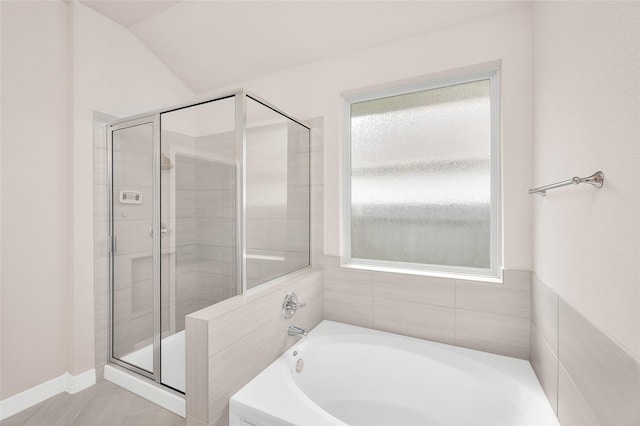 bathroom featuring vaulted ceiling, a shower stall, and a bath