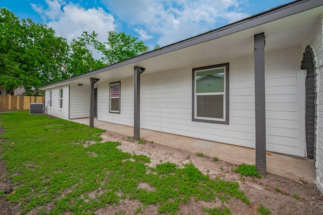 view of property exterior featuring a yard, fence, and central AC unit