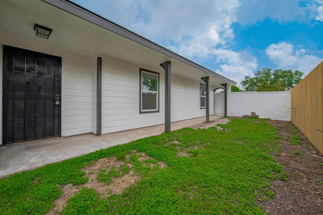 property entrance with fence and a lawn