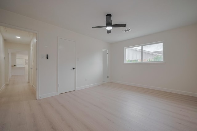 unfurnished bedroom featuring visible vents, baseboards, attic access, ceiling fan, and light wood finished floors
