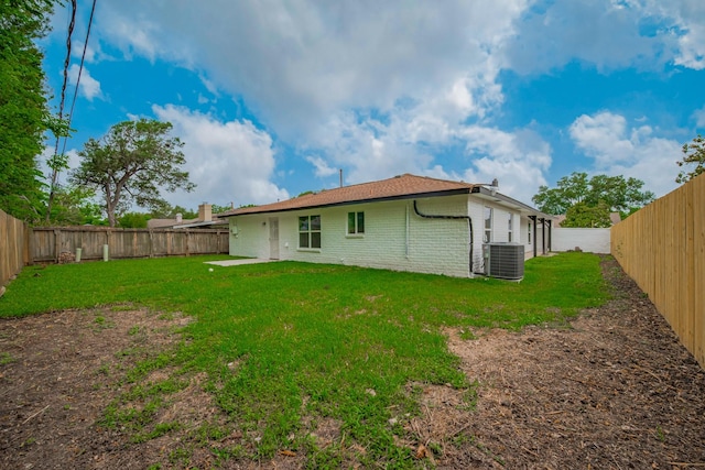 back of property with a fenced backyard, a yard, and brick siding
