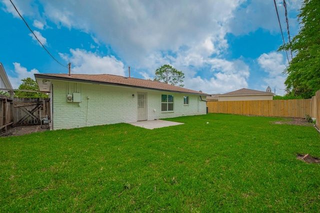 rear view of property featuring a lawn, brick siding, and a fenced backyard