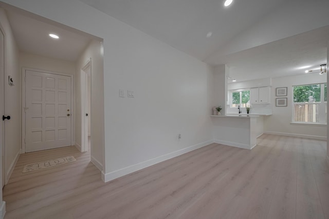 unfurnished living room featuring recessed lighting, baseboards, lofted ceiling, and light wood-type flooring