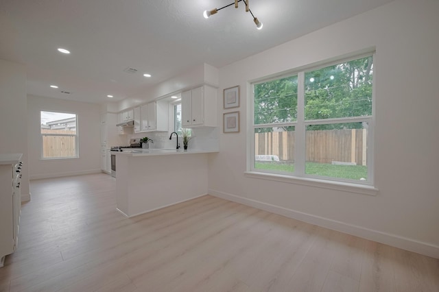 kitchen featuring baseboards, gas range oven, and light wood finished floors