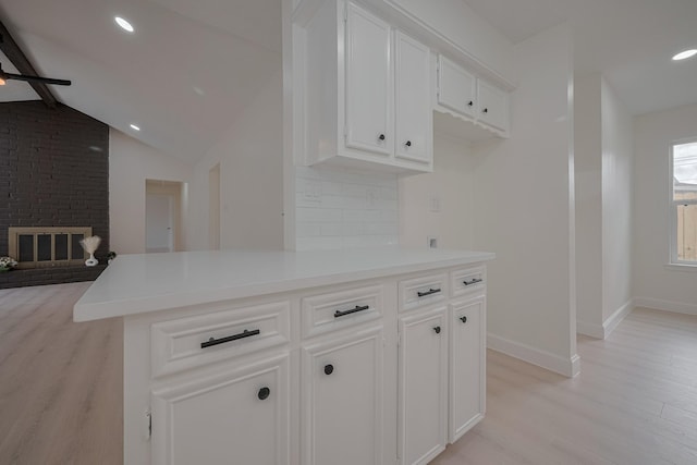 kitchen with white cabinetry, baseboards, lofted ceiling with beams, and light wood-style floors