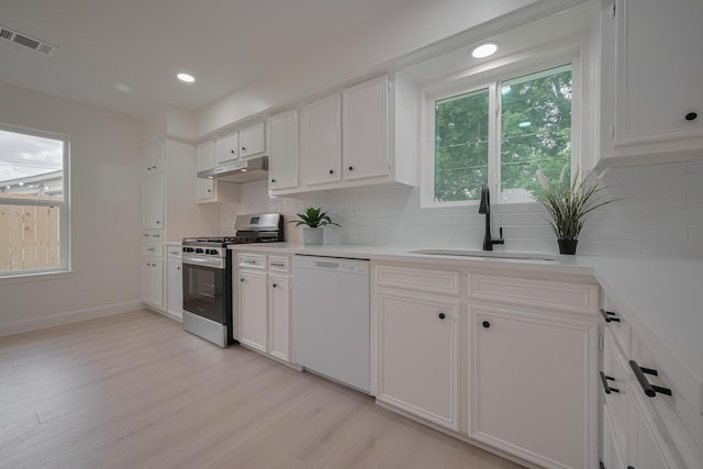 kitchen with visible vents, white dishwasher, gas range, under cabinet range hood, and a sink