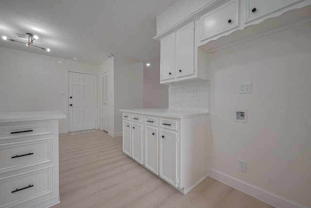 kitchen with light wood-type flooring, baseboards, and white cabinetry