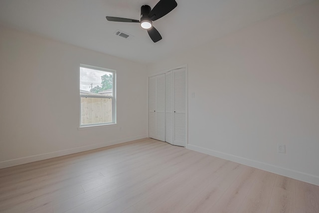 unfurnished bedroom featuring a ceiling fan, visible vents, baseboards, a closet, and light wood-style flooring