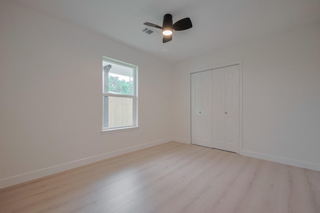 unfurnished bedroom featuring a ceiling fan, visible vents, baseboards, a closet, and light wood-style floors