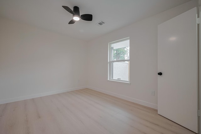 spare room with light wood-style floors, baseboards, ceiling fan, and visible vents