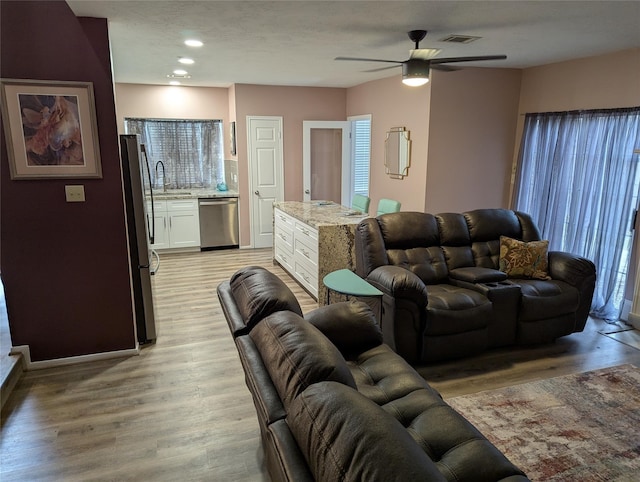 living area with light wood-style floors, a ceiling fan, and recessed lighting