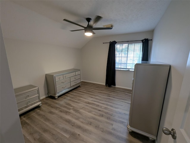 2 Skyland Pl, The Woodlands, TX 77381 - bedroom featuring lofted ceiling, wood finished floors, baseboards, a ceiling fan, and a textured ceiling