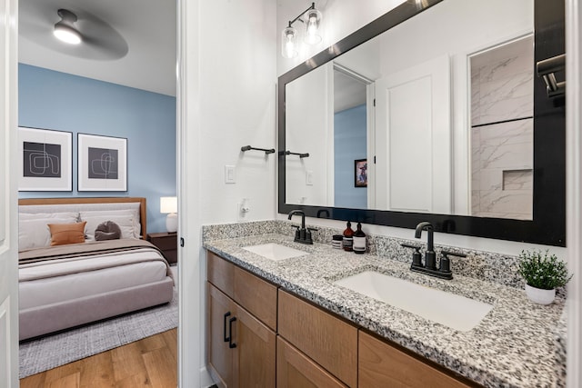 bathroom with double vanity, a sink, connected bathroom, and wood finished floors
