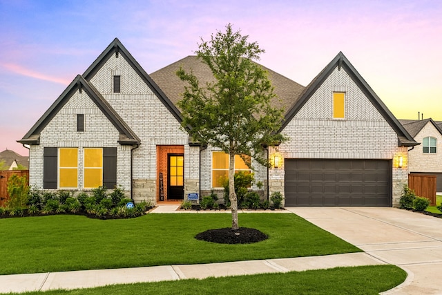 view of front of property featuring brick siding, a yard, stone siding, and concrete driveway
