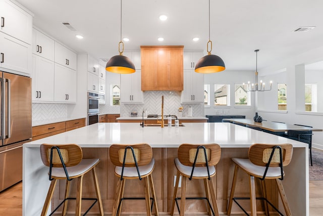 kitchen featuring a large island, visible vents, appliances with stainless steel finishes, a sink, and light countertops