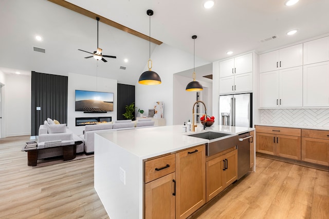 kitchen with a sink, dishwasher, high end refrigerator, light wood-type flooring, and visible vents