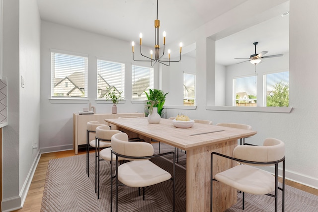 dining room with baseboards, light wood-style flooring, and ceiling fan with notable chandelier