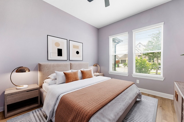 bedroom featuring baseboards, a ceiling fan, light wood-style floors, and multiple windows
