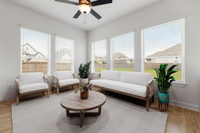sitting room with plenty of natural light, a ceiling fan, light wood finished floors, and baseboards