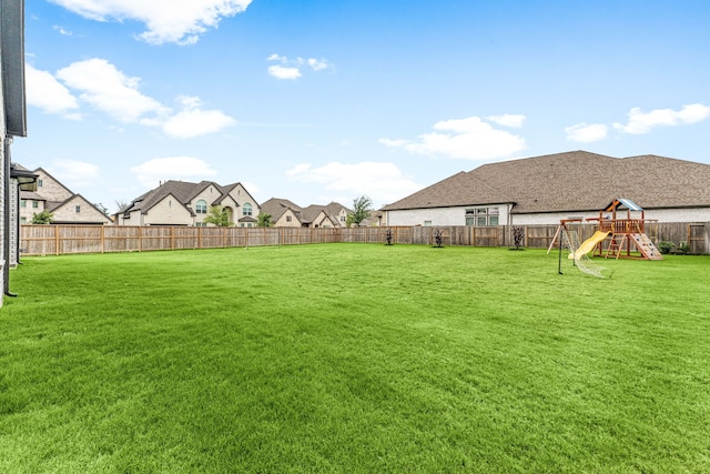 view of yard with a residential view, a fenced backyard, and a playground