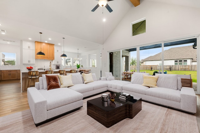 living area with light wood-style floors, high vaulted ceiling, ceiling fan, and plenty of natural light